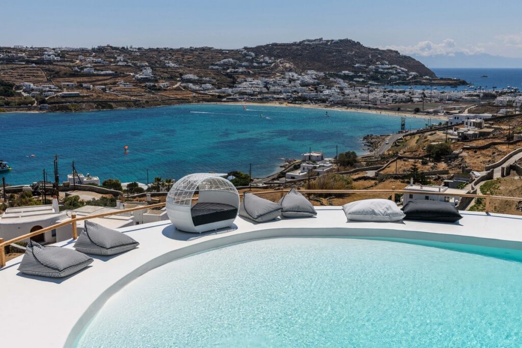 Mykonos Luxury Villa Rentals - A swimming pool overlooking a small bay and a beach in Mykonos 